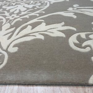 A gray and cream high-low pile rug with a swirling damask pattern rests on light wood planks.