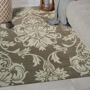 Taupe rug featuring an ornate cream damask pattern sits under a sofa on whitewashed wood floors.