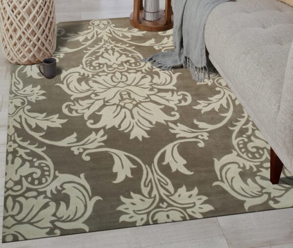Taupe rug featuring an ornate cream damask pattern sits under a sofa on whitewashed wood floors.
