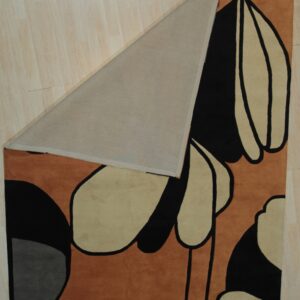 Low-pile rug in rust, black, and tan modern abstract pattern folded over light wood flooring.
