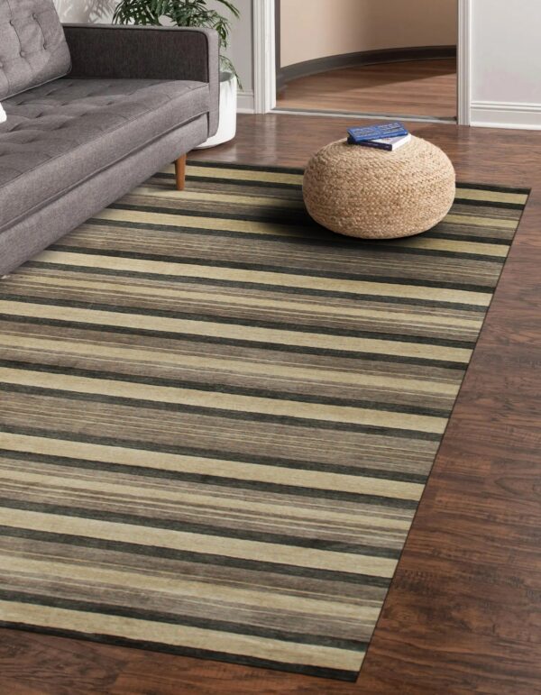 Multi-tonal striped rug covering dark wood flooring, next to a gray sofa and natural fiber ottoman.
