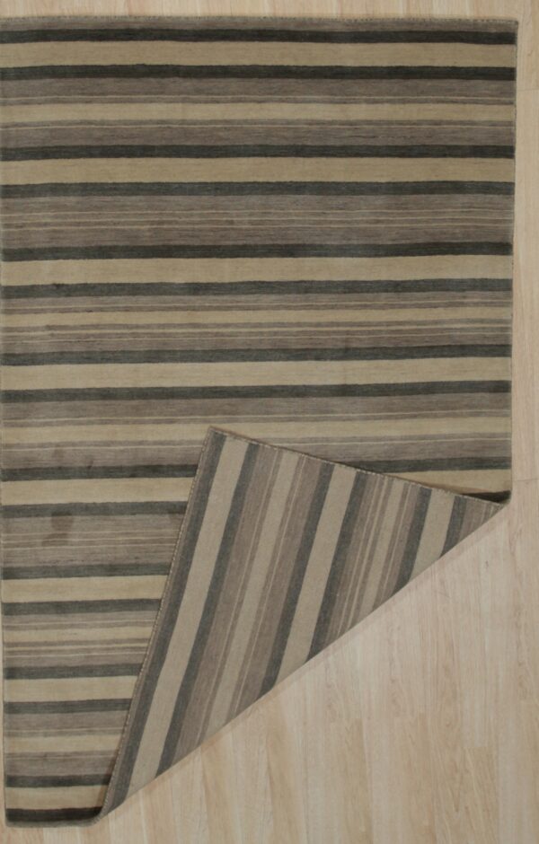 Tan and charcoal horizontally striped rug on a blonde wood floor, revealing the vertically striped backing.