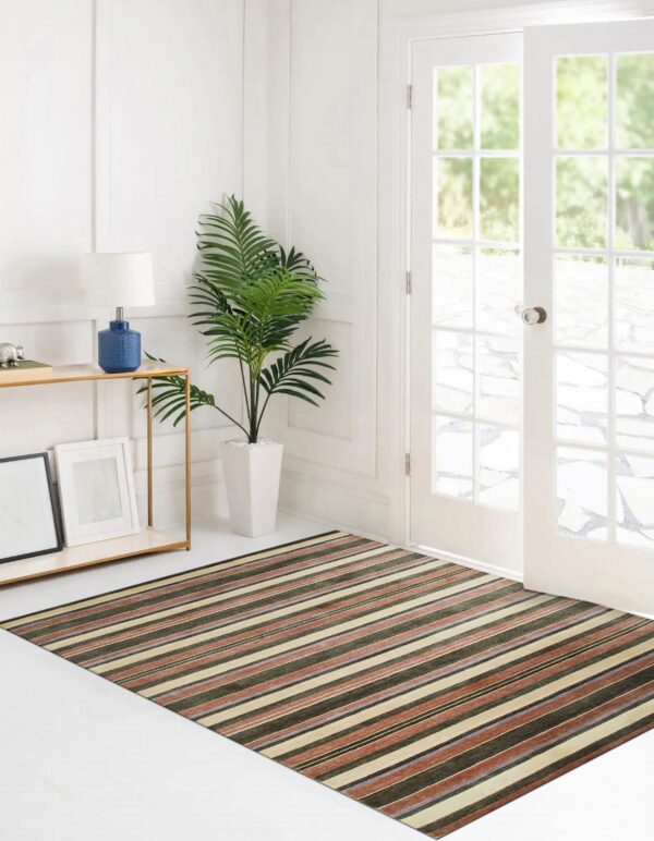 A striped rug featuring green, beige, and terracotta colors lies on white flooring by french doors.