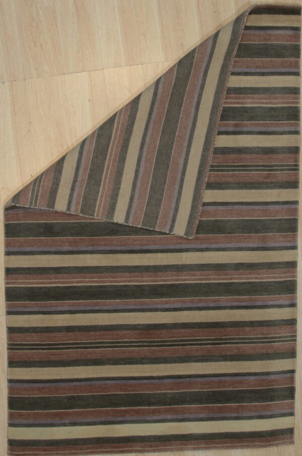 Multi-colored striped rug with horizontal stripes, folded to show vertical stripes on light wood flooring.