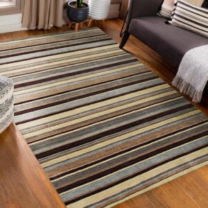 Brown, beige, and blue-gray striped rug rests on wood floors next to a dark sofa and patterned pouf.