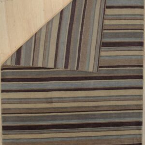 A striped rug in brown, blue, and tan is folded back on light wood flooring.