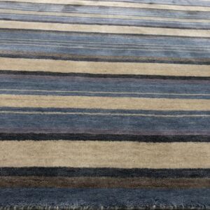 Low-angle view of a striped rug featuring blue, beige, gray, and brown colors on light wood flooring.