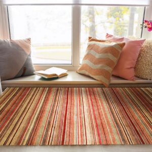 A red, orange, and olive striped rug grounds a window seat decorated with pillows and an orchid.