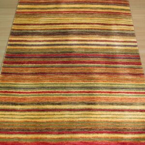 Multicolor striped rug with bands of gold, red, orange, and green on light wood flooring.