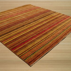 Warm-toned striped rug in gold, rust, and red hues covering light wood plank flooring.