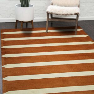 Copper and cream striped rug featuring tapered points sits beneath a fuzzy white chair and a snake plant.