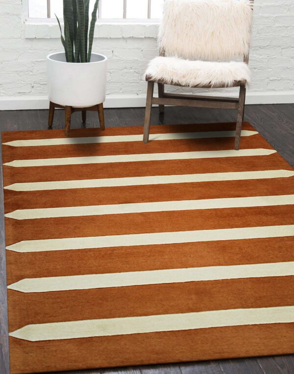 Copper and cream striped rug featuring tapered points sits beneath a fuzzy white chair and a snake plant.