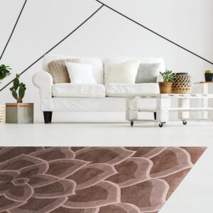 Brown carved rug with a large-scale petal design anchors a bright room with white furniture and plants.
