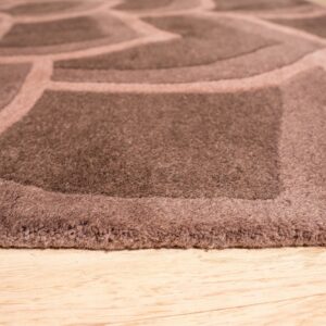 A close-up view of a brown dimensional high-pile rug with a geometric pattern on light wood floor.