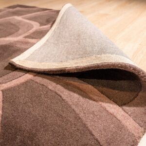 Rolled brown rug with an organic geometric pattern and carved pile on light wood flooring.
