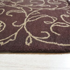 Deep brown medium-pile rug with a tan scrolling pattern lies on light wood plank flooring.