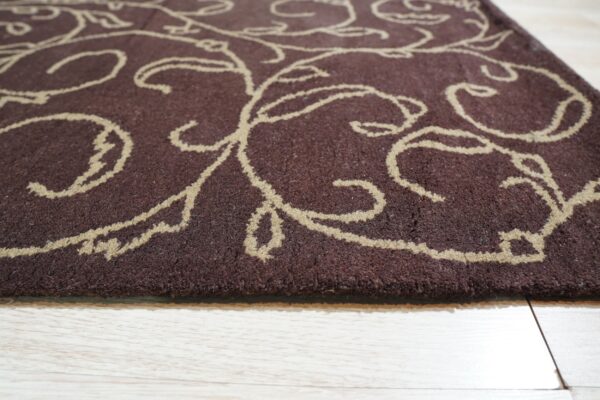 Deep brown medium-pile rug with a tan scrolling pattern lies on light wood plank flooring.