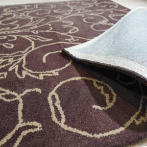 Dark brown medium-pile rug with beige scrolling pattern, rolled up on light wood floor.
