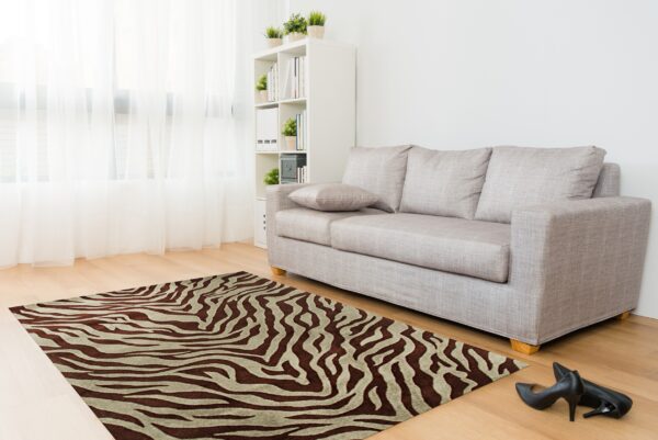 A brown and tan zebra print rug is placed on wood floors near a light gray sofa.