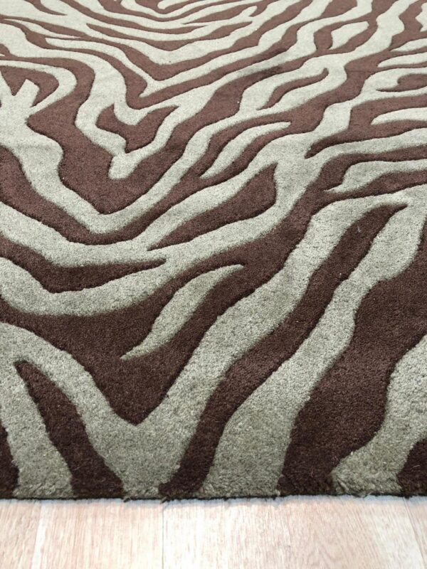 Close-up of a high-pile rug featuring dark brown and grayish-taupe stripes in a zebra pattern on light wood flooring.
