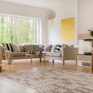 Beige and brown low-pile rug featuring an interlocking oval pattern rests on a light hardwood floor.