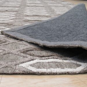 Neutral rug featuring a raised wavy pattern is rolled back, revealing its dark gray backing on wood flooring.