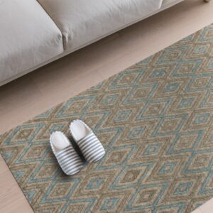 Tan and blue geometric diamond rug on wood floors with a beige sofa edge and striped slippers.