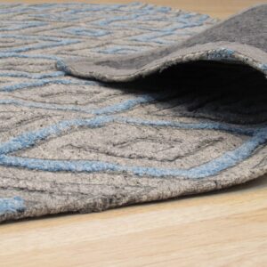 A rolled-back gray rug with bright blue zigzag lines rests on blonde wood flooring.
