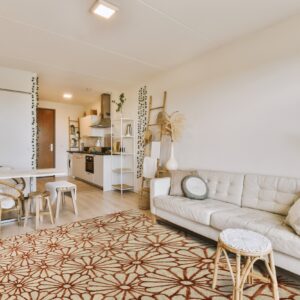 Beige rug featuring a repetitive rust-colored daisy pattern grounds a bright, bohemian living room.