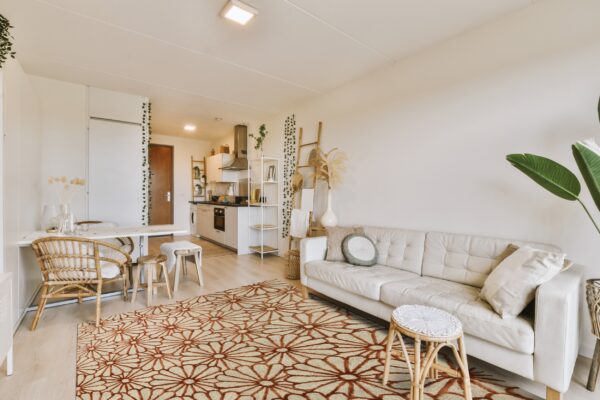 Beige rug featuring a repetitive rust-colored daisy pattern grounds a bright, bohemian living room.