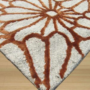 Highly textured white rug with high-pile rust lines forming a dramatic radial pattern on wood floor.