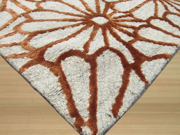 Highly textured white rug with high-pile rust lines forming a dramatic radial pattern on wood floor.