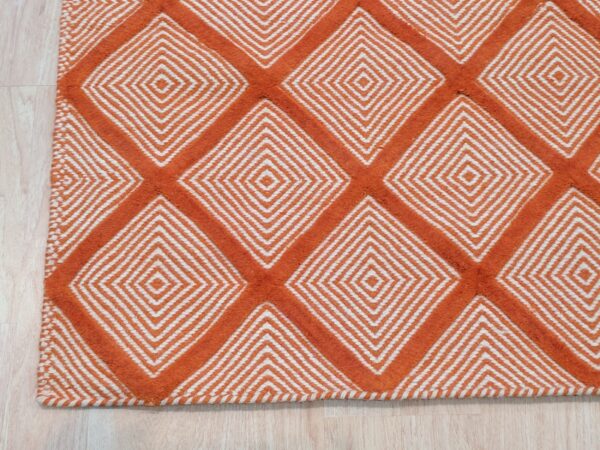 Refined luxurious yellow handmade wool rug 2 A textured orange and white rug featuring a repeating diamond geometric pattern on light wood flooring.