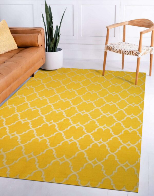 Bright yellow low-pile rug with a white moroccan lattice pattern next to a tan leather sofa and wood chair.