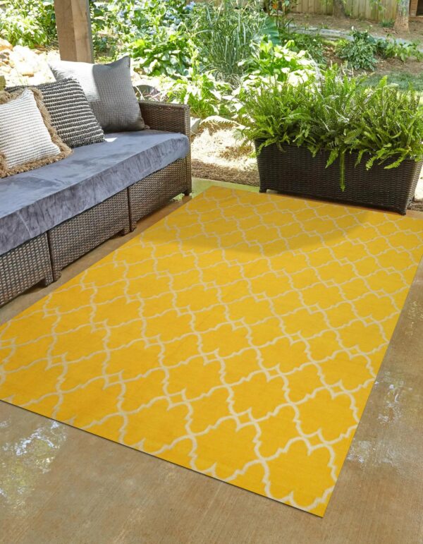 A yellow rug with a white trellis pattern covers a patio floor next to dark outdoor seating.