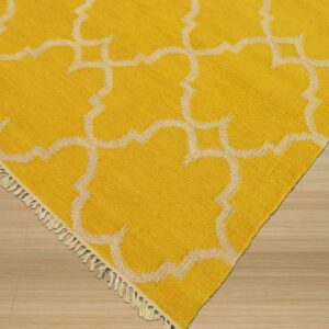 Yellow rug featuring a raised off-white Moroccan pattern and tassels shown on light wood flooring.