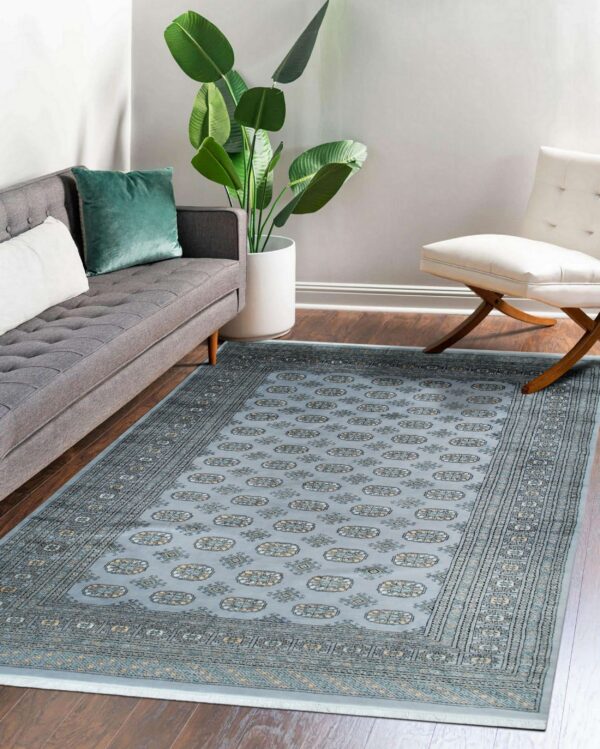 Traditional blue and gray patterned rug placed between a gray sofa and a white tufted chair.