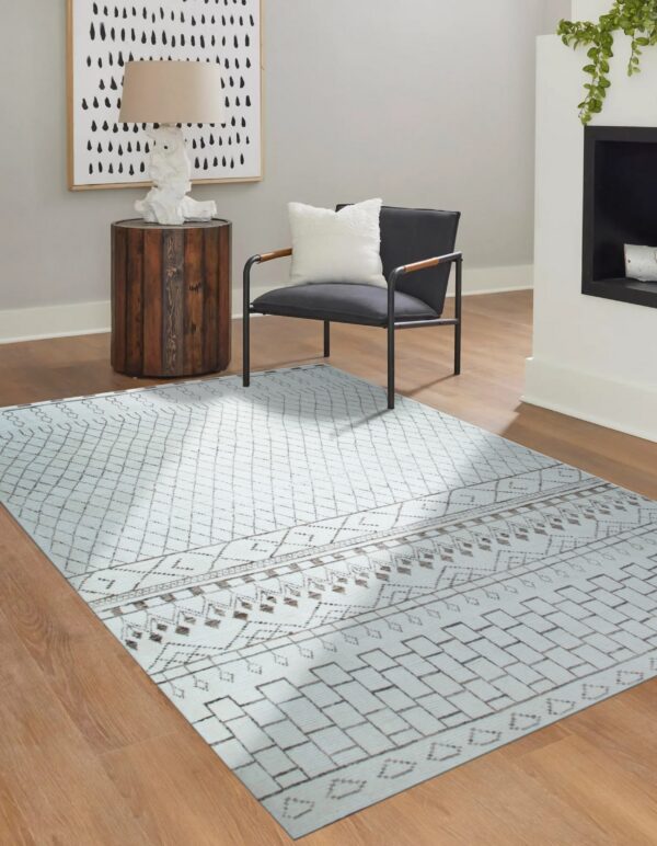 Light blue geometric rug with brown tribal patterns grounds a modern chair on wood flooring.
