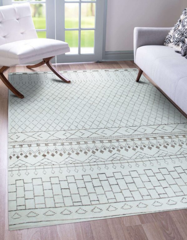 Geometric cream and brown patterned rug on wood floor with a modern white chair and gray couch.