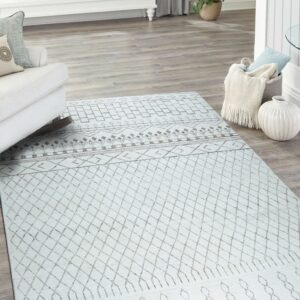 Light blue geometric rug featuring brown diamonds sits on gray wood flooring in a bright sunlit room.