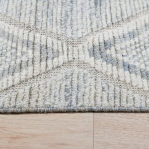 High-texture cream and gray rug with geometric pattern sits on light wood planks.
