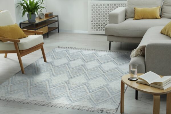 Textured flatweave rug featuring blue, tan, and white stacked diamond patterns in a bright living room setting.