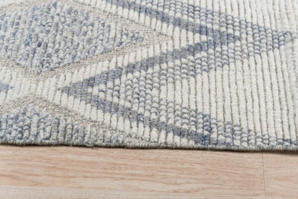 Chunky ribbed rug in blue and cream colors displaying a geometric pattern on light wood flooring.