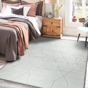 Light gray flatweave rug with abstract pattern defines a cozy bedroom beside a window.