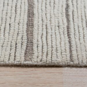 Closeup of a chunky ivory looped pile rug with vertical taupe stripes, resting on light plank wood flooring.