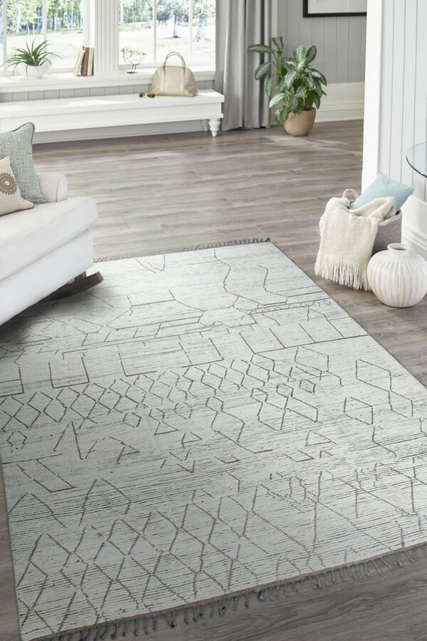 Abstract geometric lines in taupe cover a textured off-white rug on light gray wood planks.