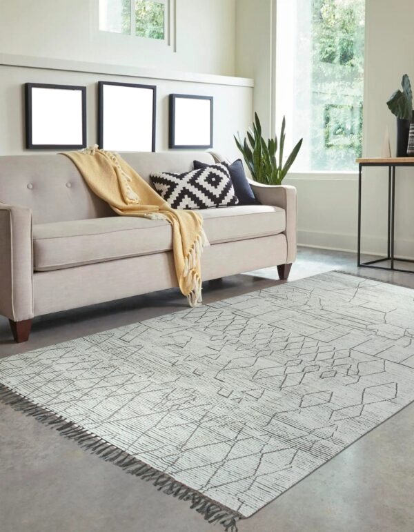 Low pile white rug featuring textured abstract gray diamond patterns under a modern light beige couch.