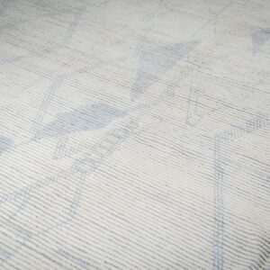 White textured rug features strong horizontal ribbing and subtle blue abstract geometric shapes.