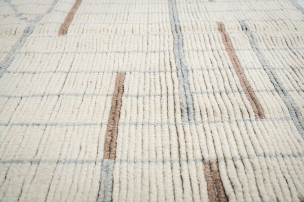 Thick-pile cream rug with a geometric grid pattern defined by taupe and light gray stripes.