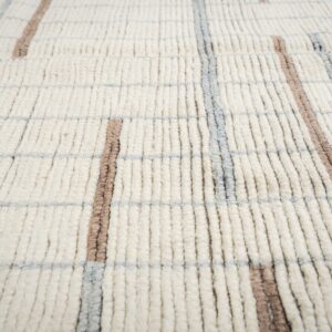 Close-up of a high-pile off-white rug featuring a grid pattern in thick taupe and light gray lines.